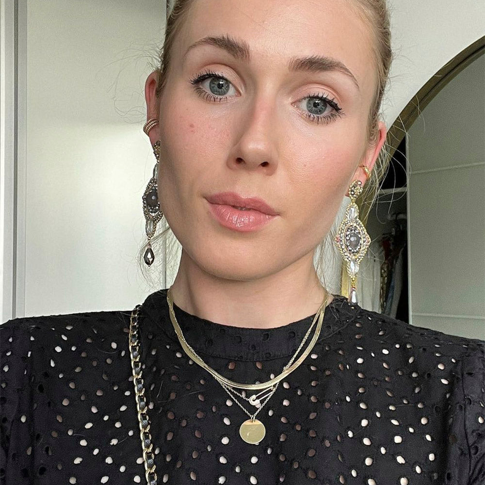 Eva Langmayr trägt große Statement Ohrringe mit rundem taupefarbenem Achatstein und silbernen und goldenen Perlen in Linz.
