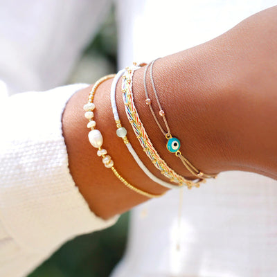 A woman showing off a three strand rainbow bracelet set with a matching nazar bracelet.