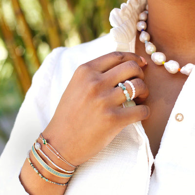 A woman showing off bright pearl jewelry and a bracelet set.