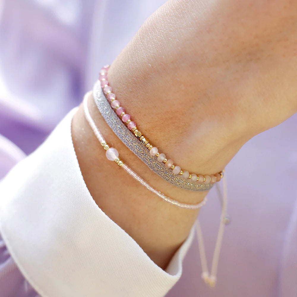 A woman wearing a light pink three strand bracelet set.