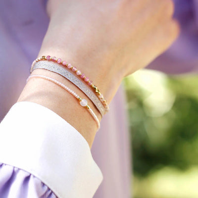 A woman wearing a three strand pink bracelet set.