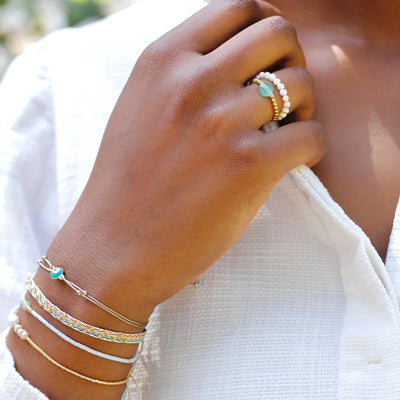 A woman displaying an arm of rainbow colourful bracelets and matching rings.
