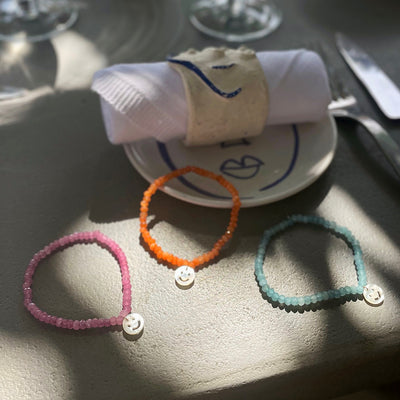 Lilac, orange, and turquoise gemstone bracelets featuring delightful mother of pearl smiley pendants