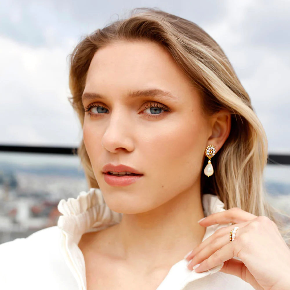 A woman wearing champagne coloured drop earrings made of natural stones and pearls with Swarovski crystals and matching rings.