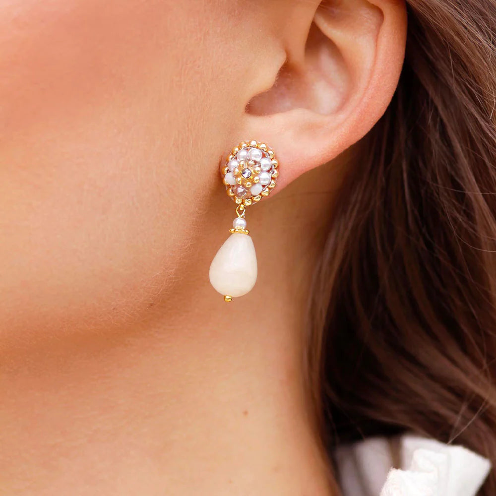 A young woman showing off pearl drop earrings.