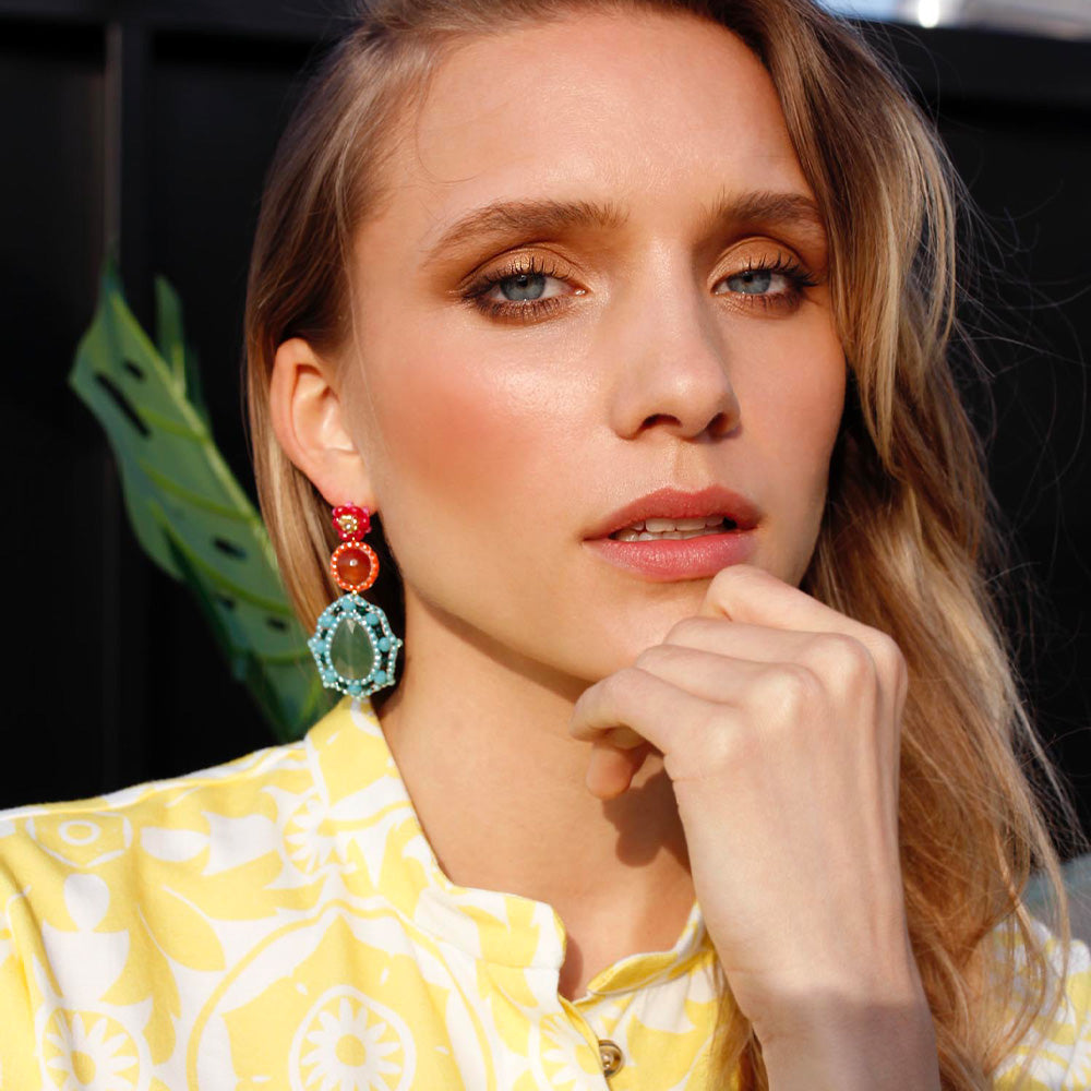 woman wearing colourful statement earrings with green quartz stone, orange camelian stone and blue, pink and orange beads