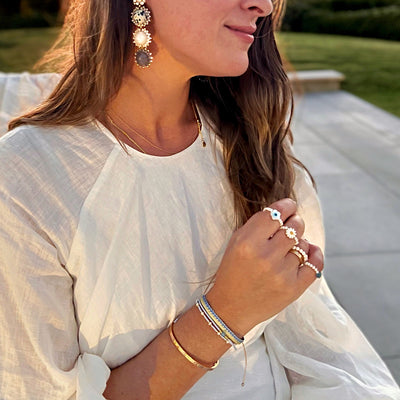 woman wearing grey-white statement earrings and light blue pearl bracelet set and white freshwater pearl stretch rings