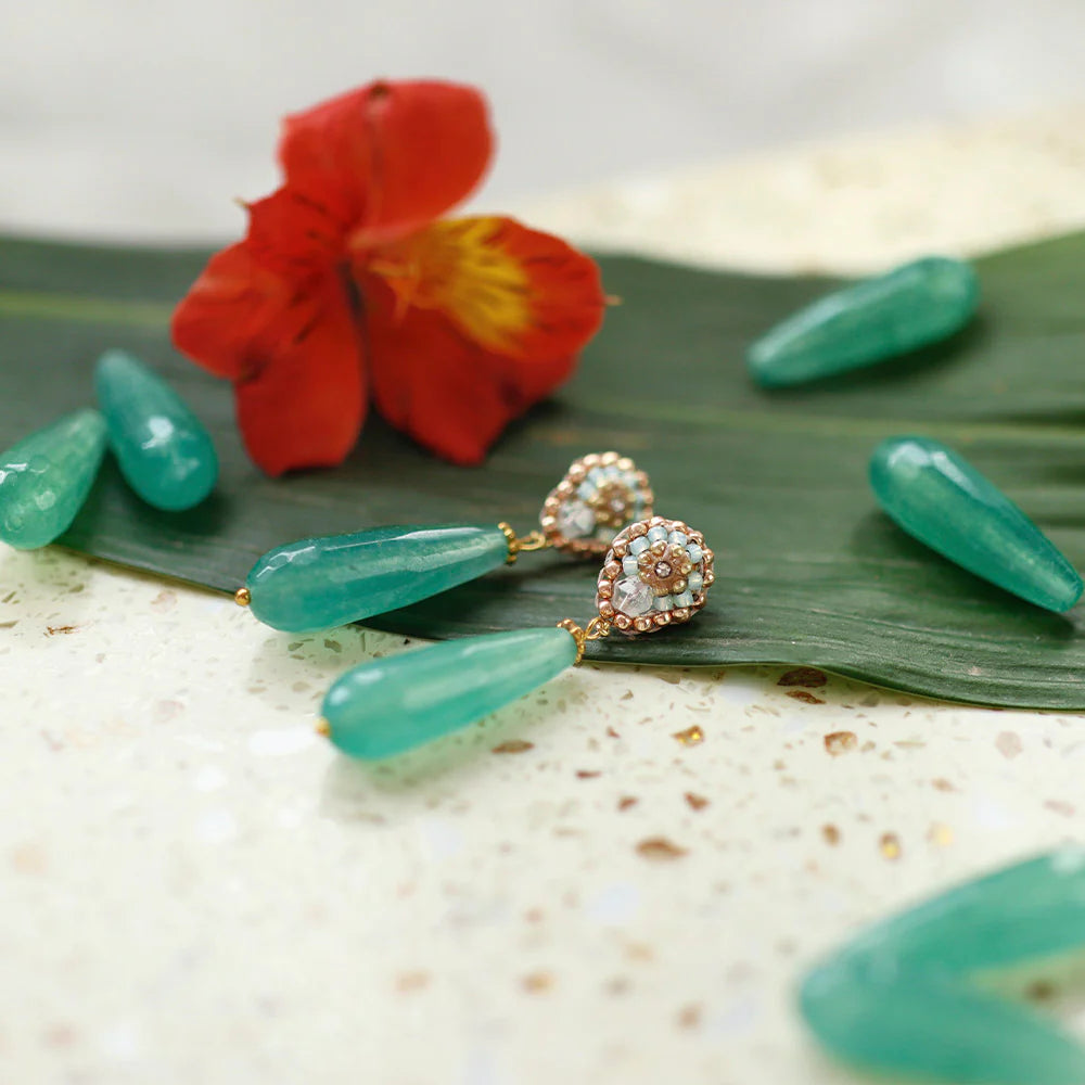 Tropical paradise: montgreen earrings with real jade displayed with tropical flowers and a leaf.