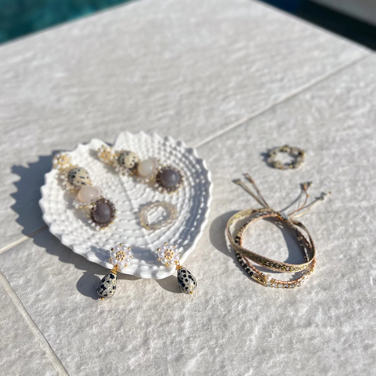 Beach vacation day: jewelry made of Dalmtion Jasper are displayed pool- side.