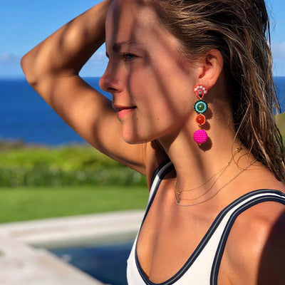 A woman wearing bohemian style colourful earrings made of real stones in front of Santa Monica beach.