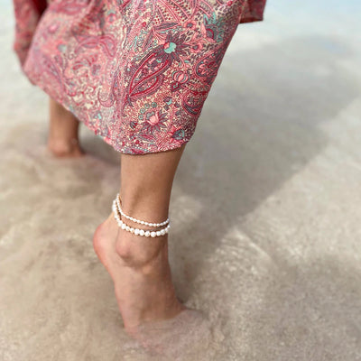 a woman at Venice beach showing off freshwater pearl layered anklets.