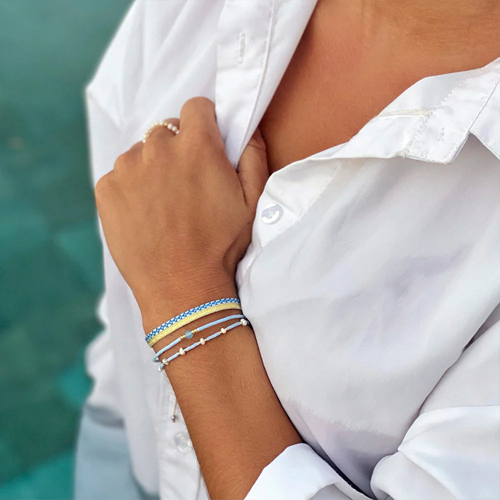 A woman wearing a beach-inspired bracelet set at the beach.