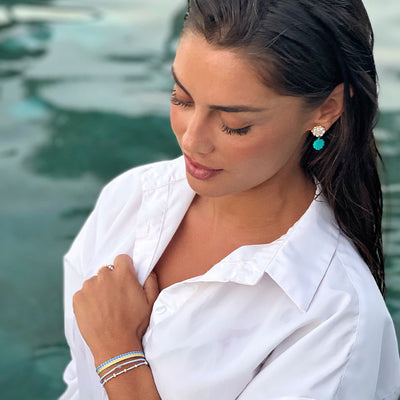 woman wearing turquoise motherr of pearl shell earrings and blue pearl bracelet set