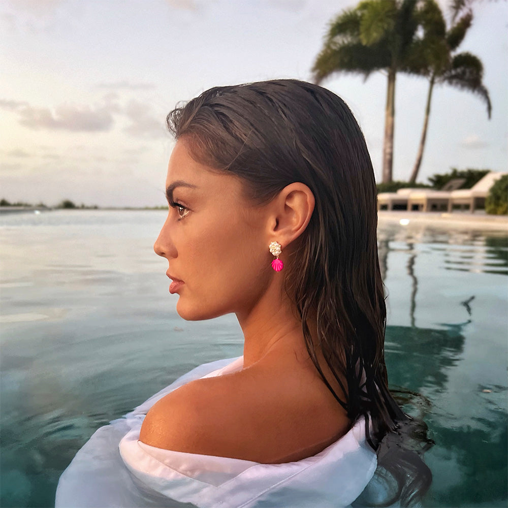 woman wearing pink mother of pearl shell charm earrings at the beach