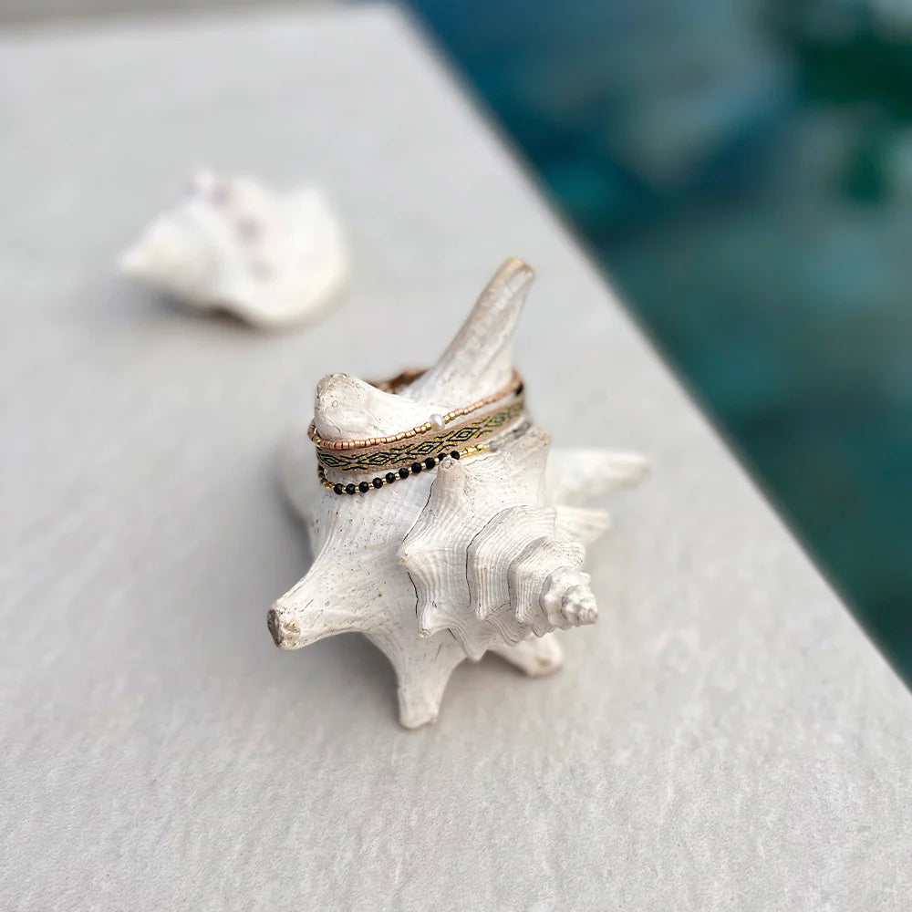 A three strand bracelet set displayed on a conch shell by Venice beach.