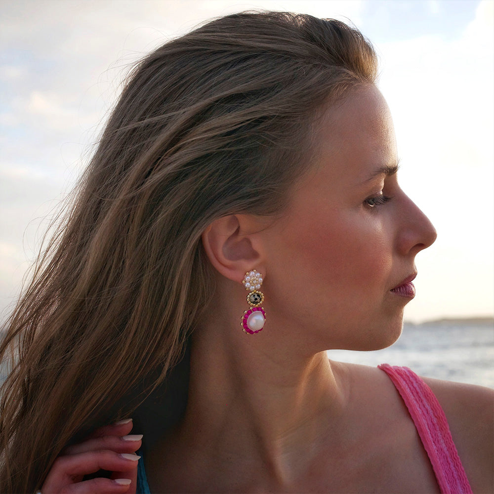 woman wearing pink summer statement gemstone earrings at the beach