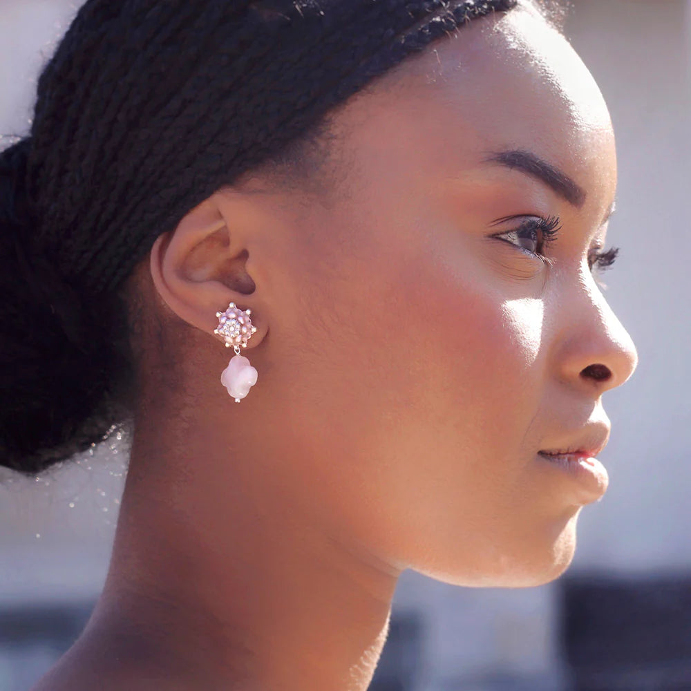 A bride on her wedding day wearing pink rose quartz earrings made of natural materials.