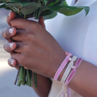 Dream wedding day: a bride wearing pink and white velvet bracelets with natural stone charms.