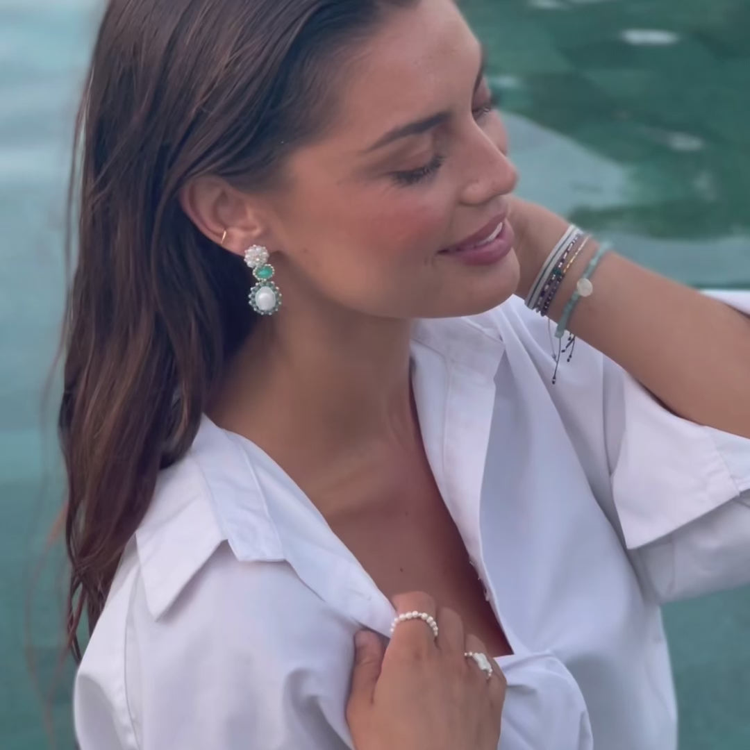 woman wearing turquoise pearl statement earrings and gemstone bracelet