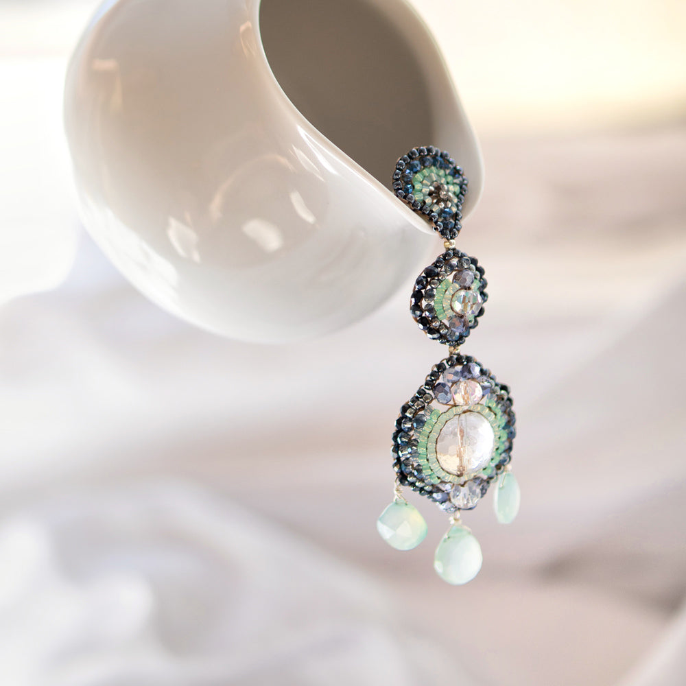 Große Ohrringe mit weißen Bergkristallen, mintgrünem Amazonit und kleinen Perlen in verschiedenen Blautönen fotografiert aus Augarten Porzellan Kanne.