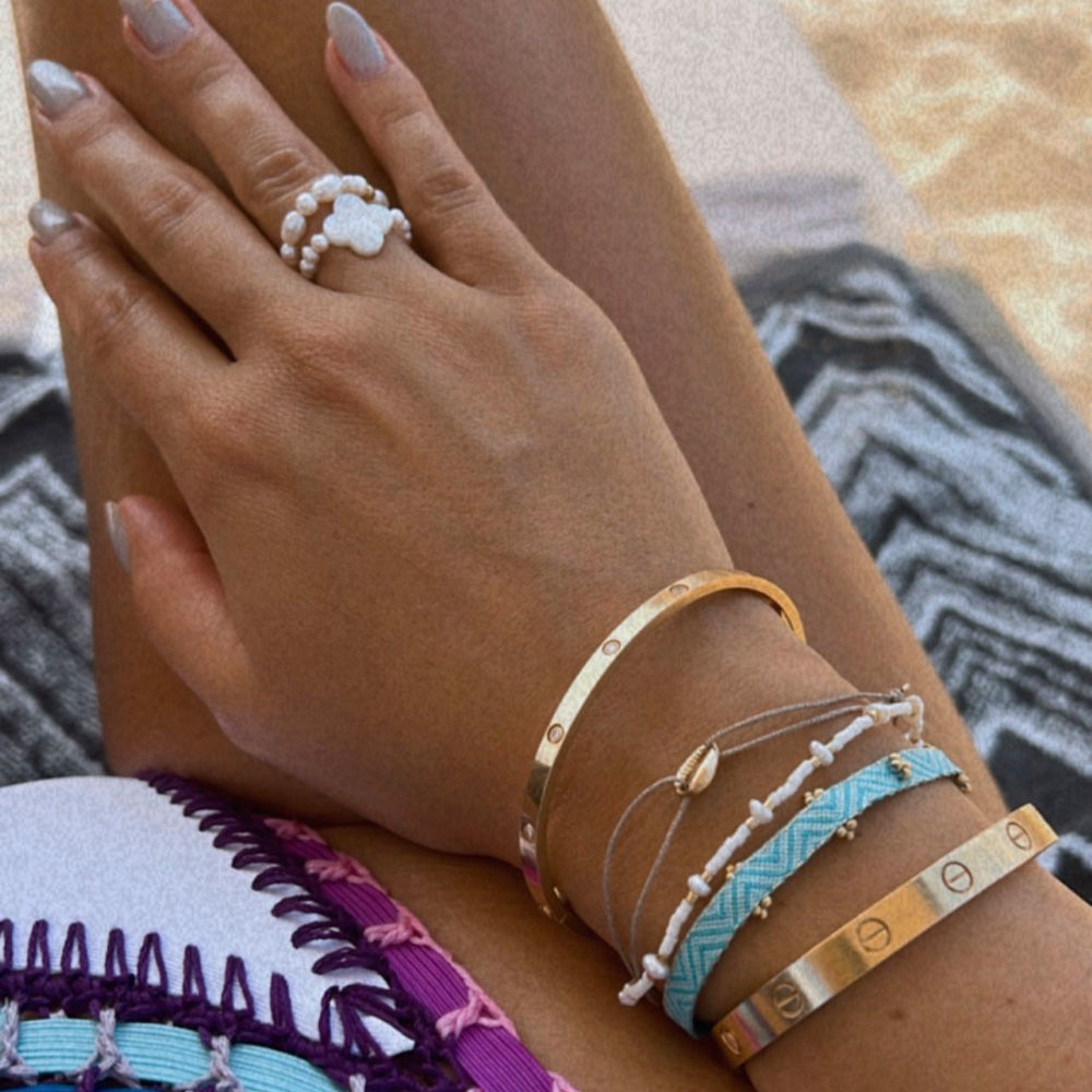 Topmodel Nadine Mirada trägt sommerliche Armband Kombination von Maschalina mit Cartier Armreifen am Strand von Mykonos.