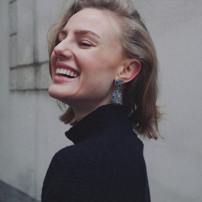 Model Victoria Karner trägt tropfenförmige Ohrringe aus Silber und hellgrauen Glasperlen in Linz.