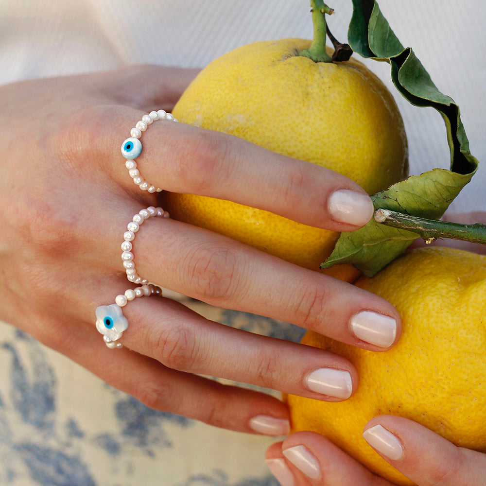 Buy handmade stretch ring with small white freshwater pearls and flower shaped nazar eye pendant out of nacre online.