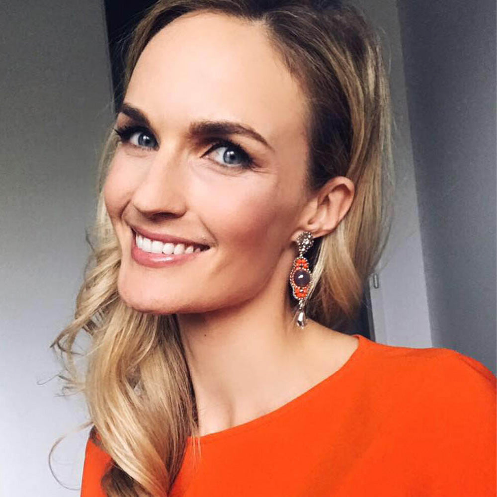 Patricia Kaiser Miss-Austria trägt lange silberne Statement-Ohrringe mit runden grauen Edelsteinen und kleinen orangefarbenen Perlen in Wien.