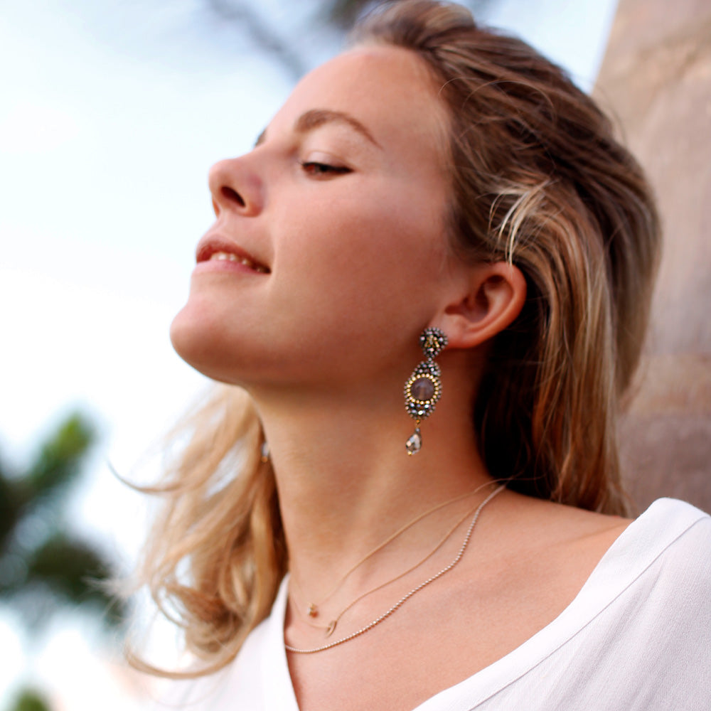 Corina Ziss wearing long grey statement earrings with round taupe-coloured agate stone and small golden beads
