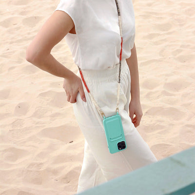 Summer beach day outfit on Lisbon beach with a turquoise ocean phone case and matching blue and leopard-print phone necklace chain.