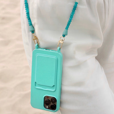 Summer beach day outfit on Lisbon beach with a turquoise ocean phone case and matching blue and turquoise phone necklace chain.