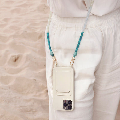 Cute summer beach outfit with a white phone case and matching turquoise gemstone phone chain necklace.