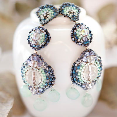 Große Ohrringe mit weißen Bergkristallen, mintgrünem Amazonit und kleinen Perlen in verschiedenen Blautönen fotografiert auf Augarten Porzellan.
